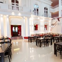 Elegantes Restaurant mit hohen wei&szlig;en W&auml;nden, roten Vorh&auml;ngen und dunklen Holztischen. Die Architektur ist klassisch mit S&auml;ulen und Balkonen., &copy; Dormero Hotel Stuttgart