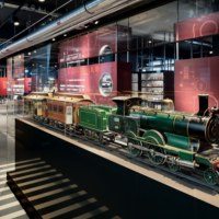 Historische Modelleisenbahnen in einer Glasvitrine im M&auml;rklineum. Im Hintergrund sind weitere Ausstellungsst&uuml;cke und Informationstafeln zu sehen., &copy; M&auml;rklin Spielwaren Vertriebs-GmbH