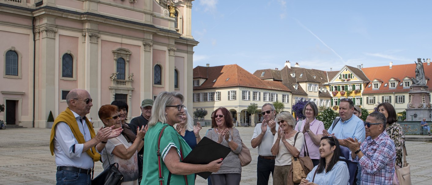 Gruppe applaudiert einer Frau vor einem historischen Gebäude in Ludwigsburg. Sonniger Tag, fröhliche Stimmung., © Tourismus & Events Ludwigsburg, Yakup Zeyrek Gruppe applaudiert einer Frau vor einem historischen Gebäude in Ludwigsburg. Sonniger Tag, fröhliche Stimmung., © Tourismus & Events Ludwigsburg, Yakup Zeyrek