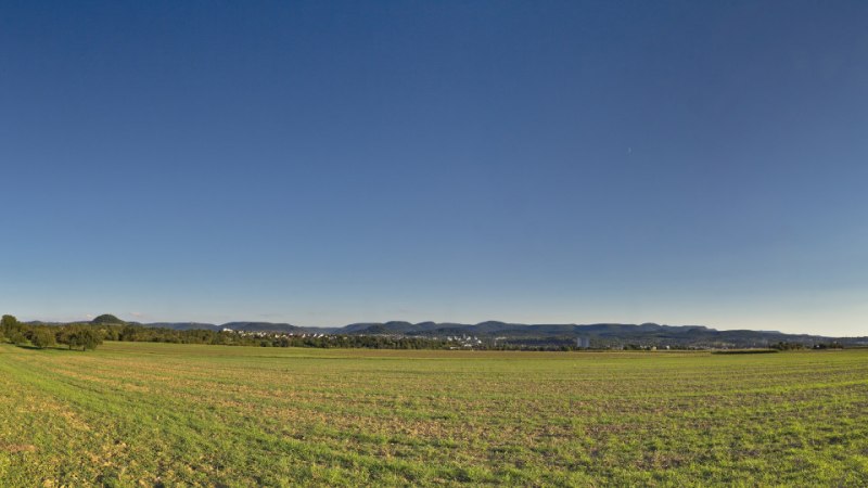 Weite Landschaft mit Feldern, einem Weg links, Strommasten rechts und einem klaren blauen Himmel. Im Hintergrund sind H&uuml;gel zu sehen., &copy; Mythos Schw&auml;bische Alb