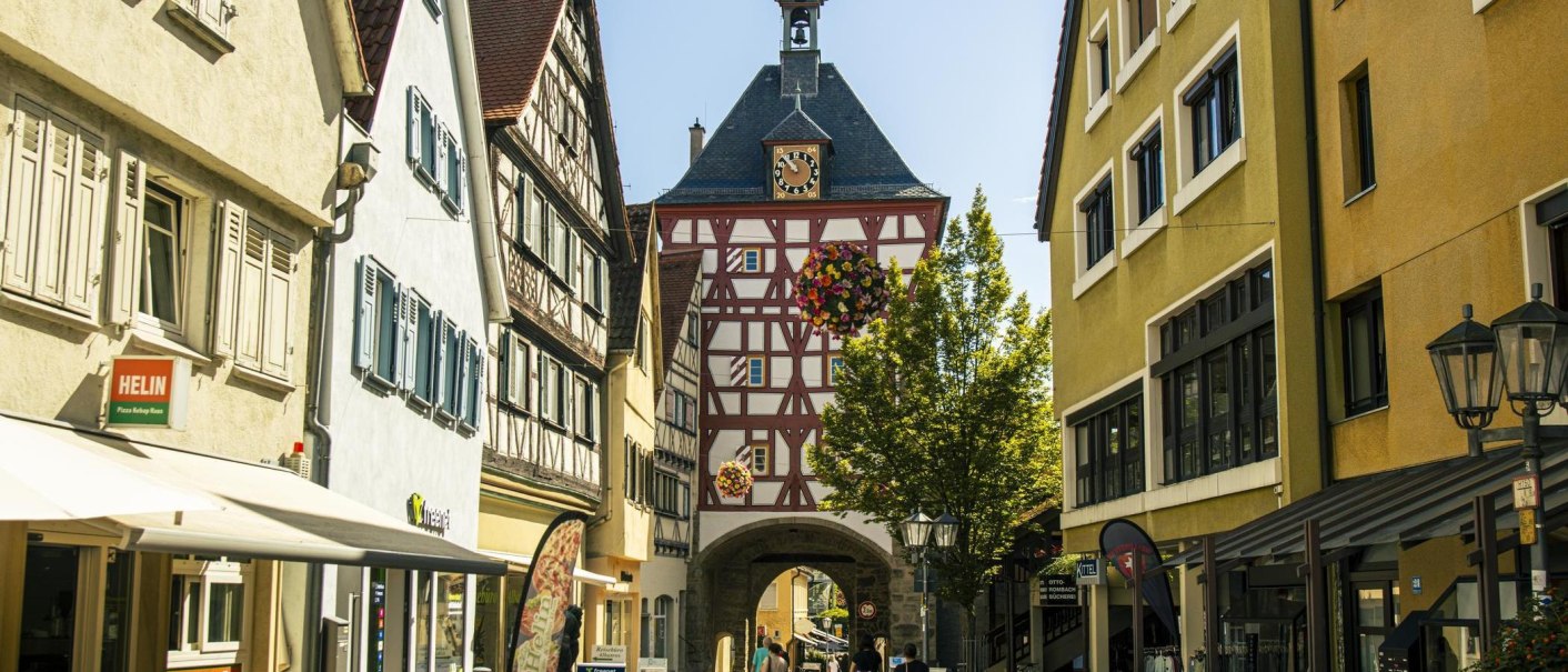 Historisches Stadttor in Bietigheim-Bissingen mit Fachwerk und Uhr, umgeben von alten Gebäuden und Geschäften., © Stuttgart Marketing GmbH, Sarah Schmid