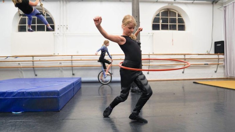 Kinder üben Zirkuskunststücke: Ein Kind mit Hula-Hoop-Reifen, ein anderes auf einem Einrad und ein drittes schwingt an einem Trapez., © Kunstschule Labyrinth Kinder üben Zirkuskunststücke: Ein Kind mit Hula-Hoop-Reifen, ein anderes auf einem Einrad und ein drittes schwingt an einem Trapez., © Kunstschule Labyrinth
