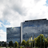 Moderne Gebäude des SI-Centrums mit Glasfassaden, umgeben von Bäumen, unter einem blauen Himmel mit Wolken., © Susanne Wegner Photography