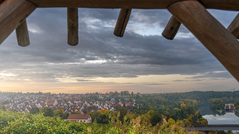 Blick von einer Plattform auf eine Stadt bei Sonnenuntergang. Im Vordergrund Holzbalken, im Hintergrund Häuser, ein Fluss und eine Brücke., © SMG, Martina Denker Blick von einer Plattform auf eine Stadt bei Sonnenuntergang. Im Vordergrund Holzbalken, im Hintergrund Häuser, ein Fluss und eine Brücke., © SMG, Martina Denker