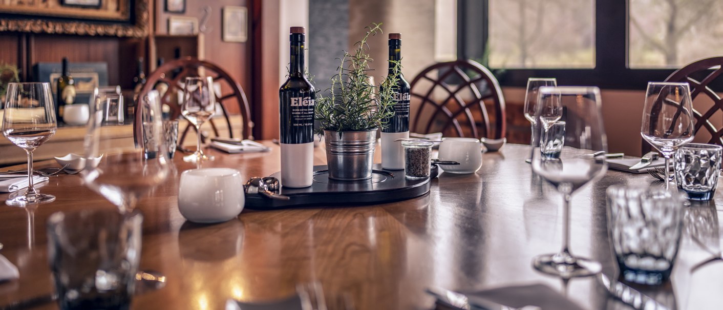 Ein eleganter Tisch in einem Restaurant, gedeckt mit Weingläsern, Flaschen und einem Kräutertopf in der Mitte. Gemütliche Atmosphäre., © Stuttgart Marriott Hotel Sindelfingen