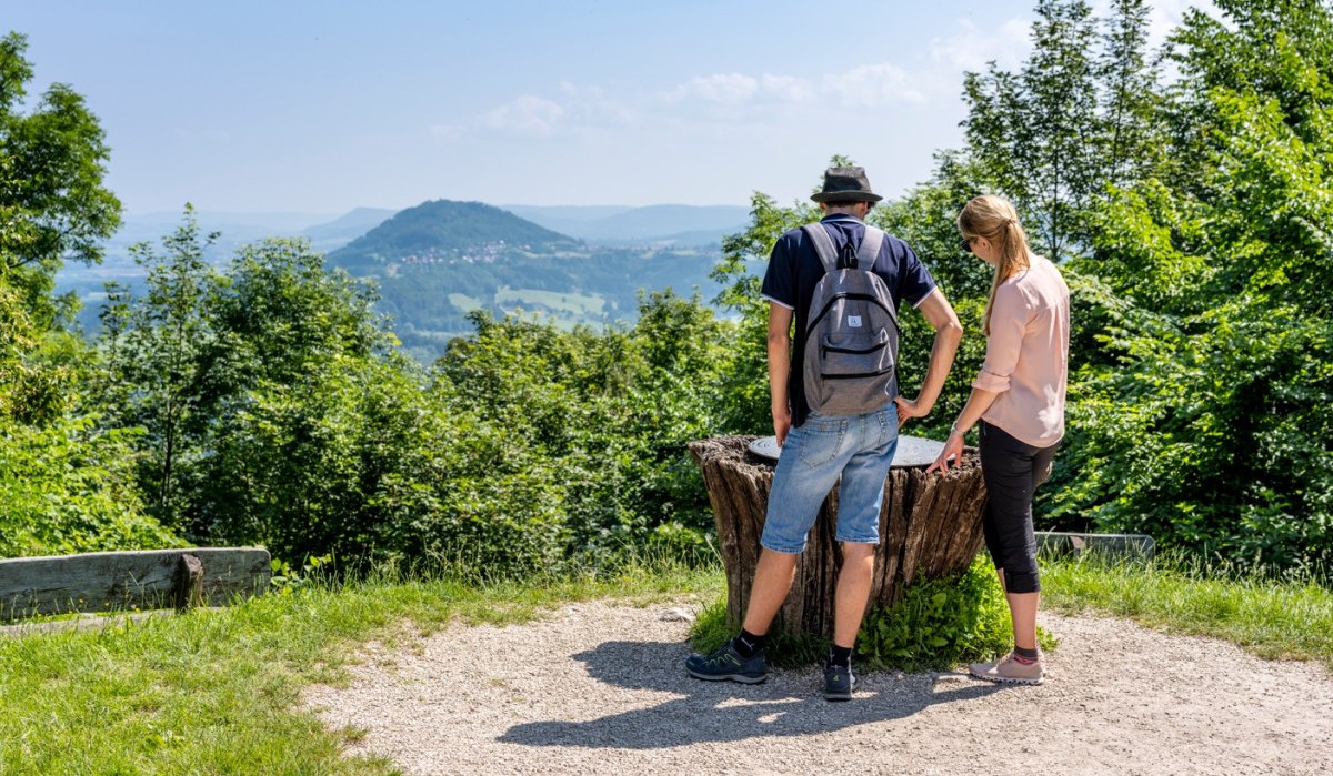 Zwei Personen betrachten von einem Aussichtspunkt aus die Landschaft mit einem bewaldeten Hügel im Hintergrund., © TMBW, Gregor Lengler Zwei Personen betrachten von einem Aussichtspunkt aus die Landschaft mit einem bewaldeten Hügel im Hintergrund., © TMBW, Gregor Lengler