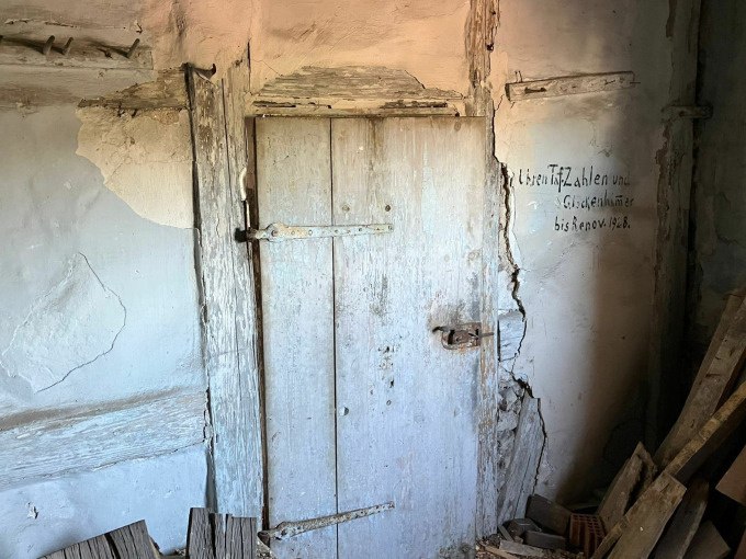 Verwitterte Holztür in einem alten Gebäude. Die Wände sind rissig und mit Holzplanken verstärkt. Eine Inschrift ist an der Wand sichtbar., © Stadtverwaltung Weil der Stadt Verwitterte Holztür in einem alten Gebäude. Die Wände sind rissig und mit Holzplanken verstärkt. Eine Inschrift ist an der Wand sichtbar., © Stadtverwaltung Weil der Stadt