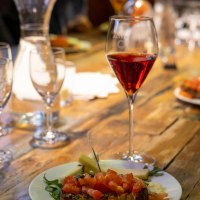 Ein Glas Rotwein steht auf einem Holztisch neben einem Teller mit Bruschetta und K&auml;sew&uuml;rfeln., &copy; Tourist Information und Ticket Service Ludwigsburg