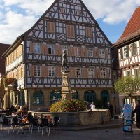 Marktplatz in Winnenden mit Fachwerkhäusern, einem zentralen Brunnen und Menschen, die den Platz beleben. Im Hintergrund ein Turm mit Uhr., © Stuttgart-Marketing GmbH