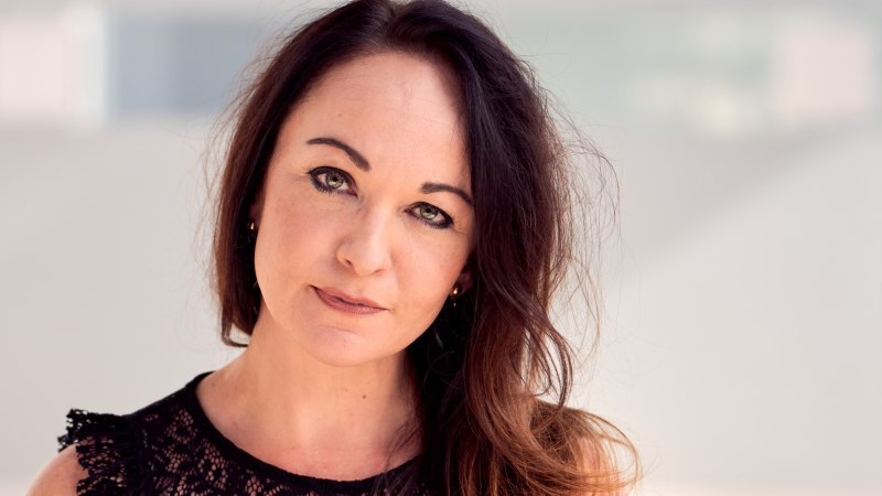 Porträt einer Frau mit dunklem Haar, die ein schwarzes Spitzenoberteil trägt. Der Hintergrund ist unscharf und hell., © copyright_Christoph Classen Porträt einer Frau mit dunklem Haar, die ein schwarzes Spitzenoberteil trägt. Der Hintergrund ist unscharf und hell., © copyright_Christoph Classen