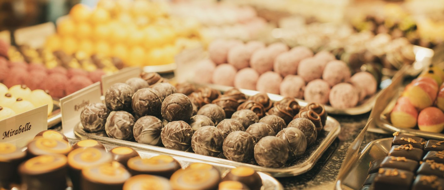 Eine Auswahl an Pralinen und Marzipan in verschiedenen Farben und Formen auf Tabletts pr&auml;sentiert., &copy; Frischmann-Marzipan-GmbH