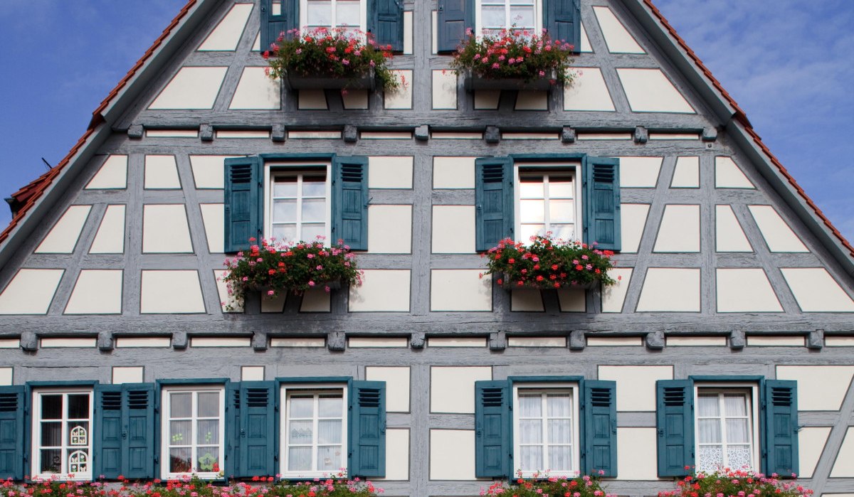 Fachwerkhaus mit blauen Fensterläden und Blumenkästen, modernes Glasportal im Erdgeschoss, blauer Himmel im Hintergrund., © Waiblingen - Stuttgart-Marketing GmbH Fachwerkhaus mit blauen Fensterläden und Blumenkästen, modernes Glasportal im Erdgeschoss, blauer Himmel im Hintergrund., © Waiblingen - Stuttgart-Marketing GmbH