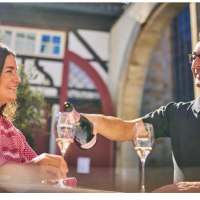 Ein Mann und eine Frau sitzen in einer Altstadt und genie&szlig;en Sekt. Der Mann schenkt der Frau ein Glas ein. Im Hintergrund Fachwerkarchitektur., &copy; Esslinger Stadtmarketing &amp; Tourismus GmbH
