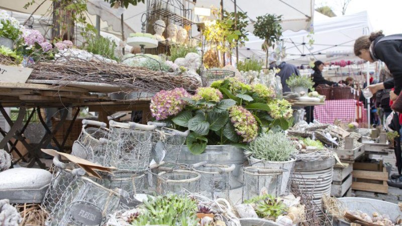 Ein Marktstand in Esslingen mit Blumen, Pflanzen und dekorativen Gegenständen. Menschen stöbern durch die Auslagen unter weißen Pavillons., © EST