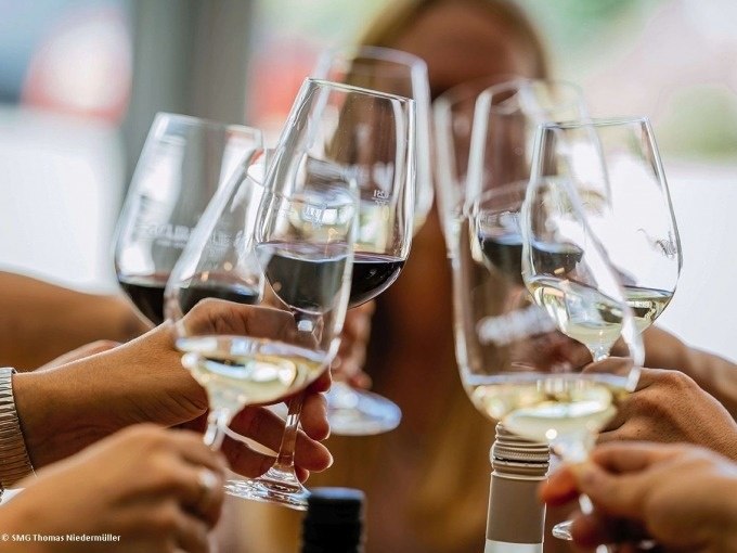 Personen sto&szlig;en mit Weingl&auml;sern an, gef&uuml;llt mit Rot- und Wei&szlig;wein. Fr&ouml;hliche Atmosph&auml;re bei einer Weintour in Stuttgart., &copy; SMG, Thomas Niederm&uuml;ller