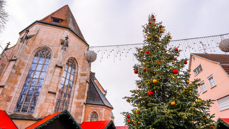 Weihnachtsmarkt mit geschmücktem Baum, Kirche im Hintergrund und Ständen mit roten Dächern. Lichterketten und Kugeln schmücken die Szene., © SMG, L.Martin Weihnachtsmarkt mit geschmücktem Baum, Kirche im Hintergrund und Ständen mit roten Dächern. Lichterketten und Kugeln schmücken die Szene., © SMG, L.Martin