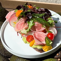 Ein belegtes Brot mit Gemüse und Salat auf einem Teller, umgeben von Avocados in einer Kiste., © Kaleya, Stuttgart Ein belegtes Brot mit Gemüse und Salat auf einem Teller, umgeben von Avocados in einer Kiste., © Kaleya, Stuttgart