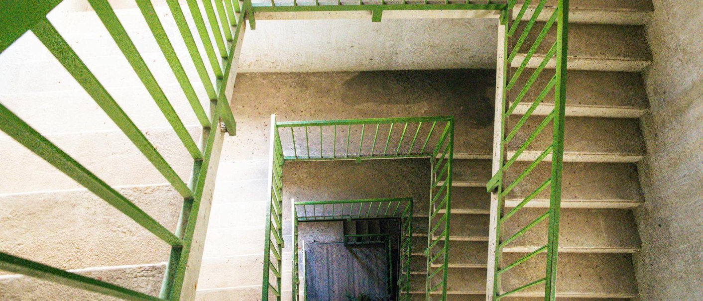 Blick von oben auf eine Wendeltreppe mit grünen Geländern in einem Betongebäude. Die Treppe führt spiralförmig nach unten., © Stuttgart-Marketing GmbH, Sarah Schmid