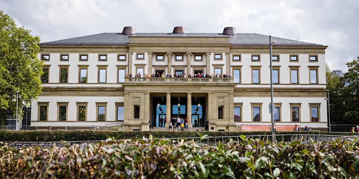 Das Stadtpalais – Museum für Stuttgart, ein klassizistisches Gebäude mit Menschen auf dem Balkon, umgeben von Bäumen und Hecken., © @ die arge lola / Kai Loges + Andreas Langen Das Stadtpalais – Museum für Stuttgart, ein klassizistisches Gebäude mit Menschen auf dem Balkon, umgeben von Bäumen und Hecken., © @ die arge lola / Kai Loges + Andreas Langen