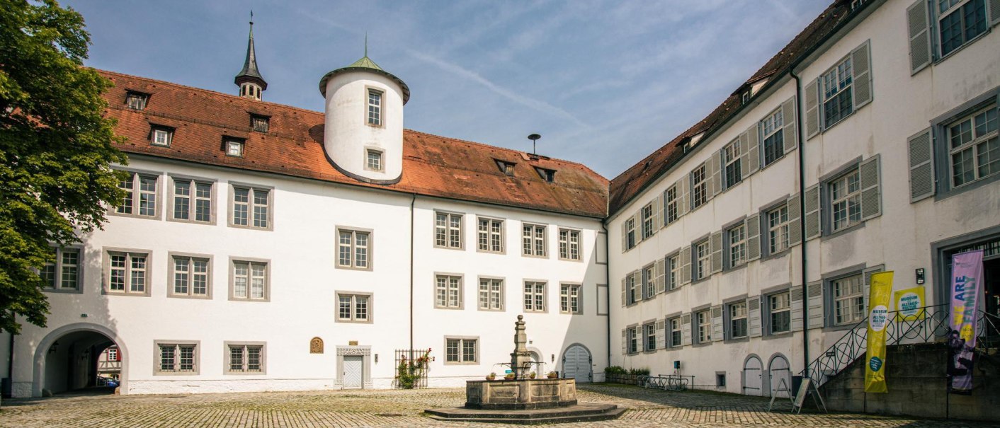 Der Innenhof von Schloss Waldenbuch zeigt wei&szlig;e Geb&auml;ude mit roten D&auml;chern und einen zentralen Brunnen. Ein blauer Himmel rundet die Szene ab., &copy; SMG, Sarah Schmid