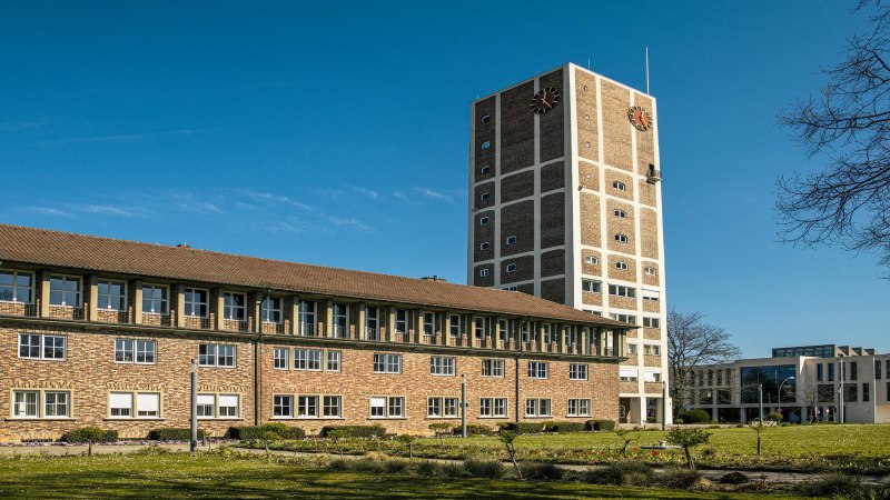 Das Rathaus Kornwestheim mit einem hohen Turm und einem modernen Anbau, umgeben von einem grünen Rasen unter blauem Himmel., © SMG, Sarah Schmid Das Rathaus Kornwestheim mit einem hohen Turm und einem modernen Anbau, umgeben von einem grünen Rasen unter blauem Himmel., © SMG, Sarah Schmid