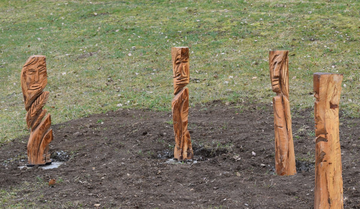 Vier geschnitzte Holzskulpturen stehen auf einem Erdstreifen, umgeben von Gras. Die Skulpturen zeigen abstrakte Gesichter., © Gemeinde Böbingen Vier geschnitzte Holzskulpturen stehen auf einem Erdstreifen, umgeben von Gras. Die Skulpturen zeigen abstrakte Gesichter., © Gemeinde Böbingen