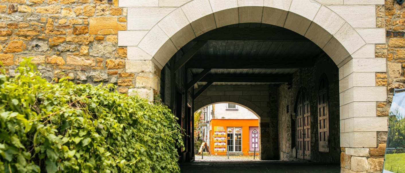 Ein steinerner Torbogen führt zu einem orangefarbenen Gebäude. Links sind grüne Pflanzen, rechts eine Steinmauer., © Stuttgart-Marketing GmbH, Sarah Schmid Ein steinerner Torbogen führt zu einem orangefarbenen Gebäude. Links sind grüne Pflanzen, rechts eine Steinmauer., © Stuttgart-Marketing GmbH, Sarah Schmid