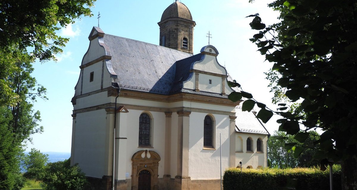 Die St. Maria Wallfahrtskirche Hohenrechberg steht inmitten gr&uuml;ner B&auml;ume. Das Geb&auml;ude hat eine helle Fassade und einen markanten Turm., &copy; Foto: Walter Laible