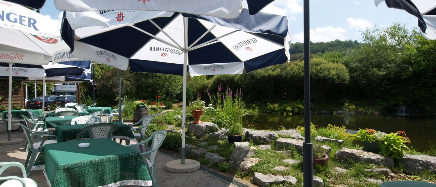 Terrasse mit grünen Tischen und Stühlen unter Sonnenschirmen. Im Hintergrund ein Fluss und grüne Vegetation., © © H-Hotels.com Terrasse mit grünen Tischen und Stühlen unter Sonnenschirmen. Im Hintergrund ein Fluss und grüne Vegetation., © © H-Hotels.com