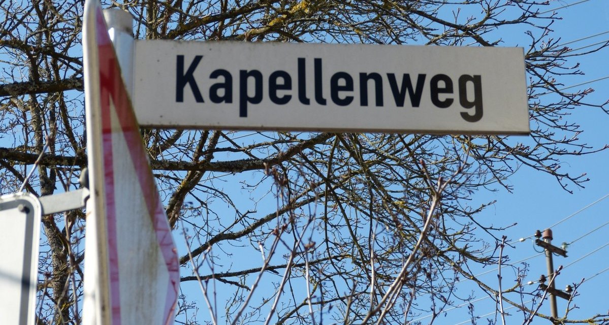 Ein Straßenschild mit der Aufschrift 'Kapellenweg' vor einem blauen Himmel und kahlen Ästen., © Natur.Nah. Schönbuch & Heckengäu Ein Straßenschild mit der Aufschrift 'Kapellenweg' vor einem blauen Himmel und kahlen Ästen., © Natur.Nah. Schönbuch & Heckengäu