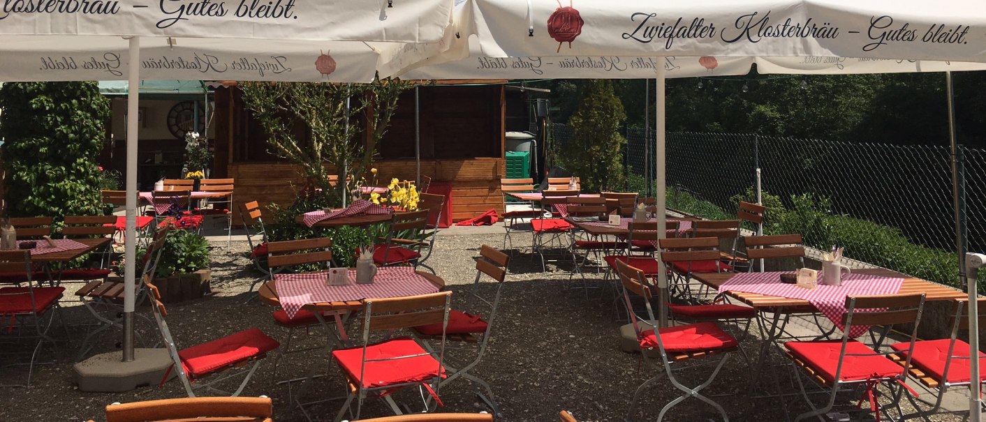 Ein gemütlicher Biergarten mit rot-weiß karierten Tischdecken und Zwiefalter Klosterbräu-Sonnenschirmen unter blauem Himmel., © Schwäbisches Gasthaus Ein gemütlicher Biergarten mit rot-weiß karierten Tischdecken und Zwiefalter Klosterbräu-Sonnenschirmen unter blauem Himmel., © Schwäbisches Gasthaus