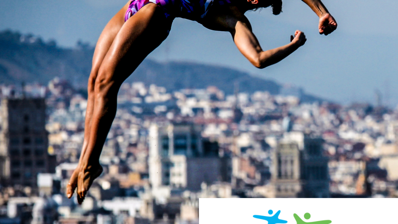 Eine Sportlerin in einem lila Badeanzug springt vor einer Stadtlandschaft in die Luft. Unten rechts ist das Logo von Sport & Kultur zu sehen., © Benjamin Lau Eine Sportlerin in einem lila Badeanzug springt vor einer Stadtlandschaft in die Luft. Unten rechts ist das Logo von Sport & Kultur zu sehen., © Benjamin Lau