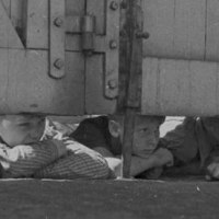 Mehrere Kinder liegen auf dem Boden und schauen neugierig unter einem gro&szlig;en Holztor hindurch., &copy; Staatsarchiv Ludwigsburg