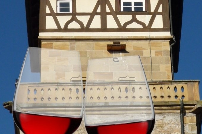Zwei gefüllte Weingläser vor einem historischen Fachwerkgebäude mit blauer Himmel im Hintergrund., © WTM GmbH Waiblingen