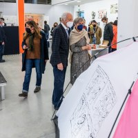 Besucher in einer Kunstgalerie betrachten eine Ausstellung. Sie tragen Masken und stehen vor einem Zelt mit Zeichnungen. Die Galerie hat bunte Säulen., © Kunsthalle Göppingen