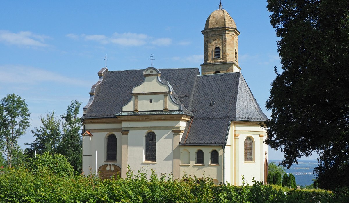 Barockkirche St. Maria Rechberg mit markantem Turm, umgeben von Bäumen und Sträuchern, unter blauem Himmel., © Foto Walter Laible Barockkirche St. Maria Rechberg mit markantem Turm, umgeben von Bäumen und Sträuchern, unter blauem Himmel., © Foto Walter Laible