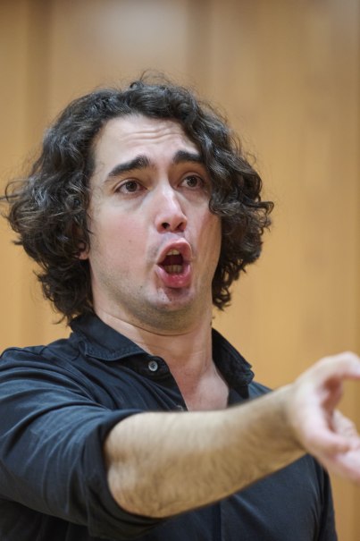Ein Mann mit lockigem Haar singt leidenschaftlich und gestikuliert mit der Hand. Er trägt ein schwarzes Hemd und steht vor einem unscharfen Hintergrund., © www.peter-oppenlaender.de Ein Mann mit lockigem Haar singt leidenschaftlich und gestikuliert mit der Hand. Er trägt ein schwarzes Hemd und steht vor einem unscharfen Hintergrund., © www.peter-oppenlaender.de
