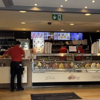 Ein Eiscaf&eacute; mit einer Theke voller bunter Eissorten. Zwei Mitarbeiter in roten Hemden bedienen Kunden. Im Hintergrund sind Men&uuml;s und Gl&auml;ser zu sehen., &copy; cStadtN&uuml;rtingen