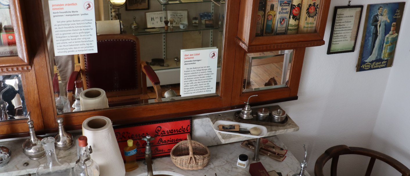 Antiker Friseursalon mit Rasierutensilien, Spiegel und Werbeschildern im Stadtmuseum Gerlingen. Historische Atmosphäre mit alten Produkten., © Stadtmuseum Gerlingen Antiker Friseursalon mit Rasierutensilien, Spiegel und Werbeschildern im Stadtmuseum Gerlingen. Historische Atmosphäre mit alten Produkten., © Stadtmuseum Gerlingen