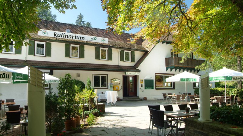 Ein Restaurant mit Terrasse, umgeben von B&auml;umen. Tische und St&uuml;hle stehen unter Sonnenschirmen. Das Geb&auml;ude hat gr&uuml;ne Fensterl&auml;den., &copy; Kulinarium an der Glems