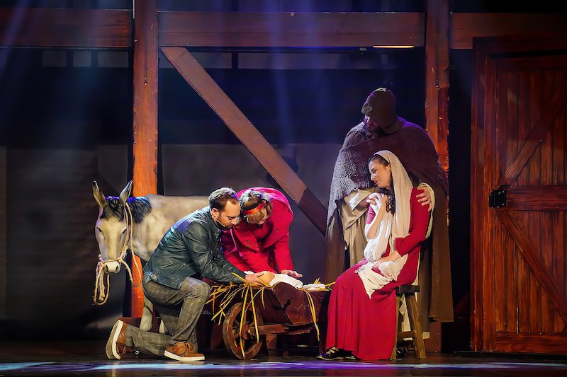 Schauspieler stellen eine Krippenszene dar, mit einem Esel, einer Krippe und Figuren in historischen Kostümen auf einer Bühne., © Wacky Productions GmbH Schauspieler stellen eine Krippenszene dar, mit einem Esel, einer Krippe und Figuren in historischen Kostümen auf einer Bühne., © Wacky Productions GmbH