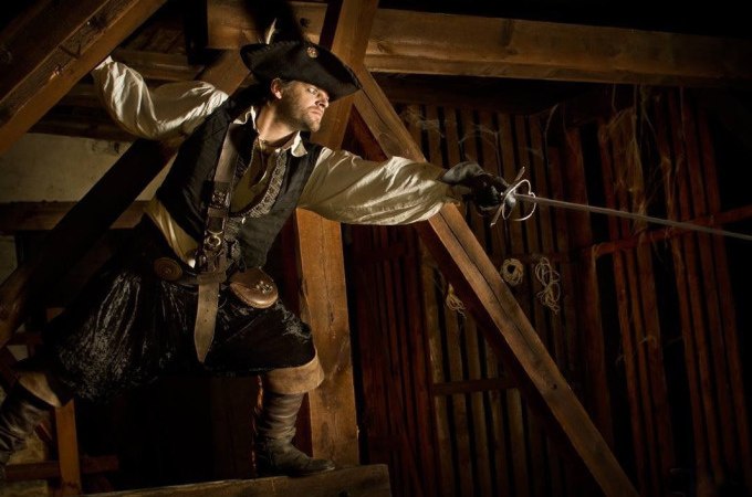 Person in Piratenkostüm posiert mit Degen in einem hölzernen Raum, dramatische Beleuchtung., © Esslinger Stadtmarketing &amp; Tourismus GmbH