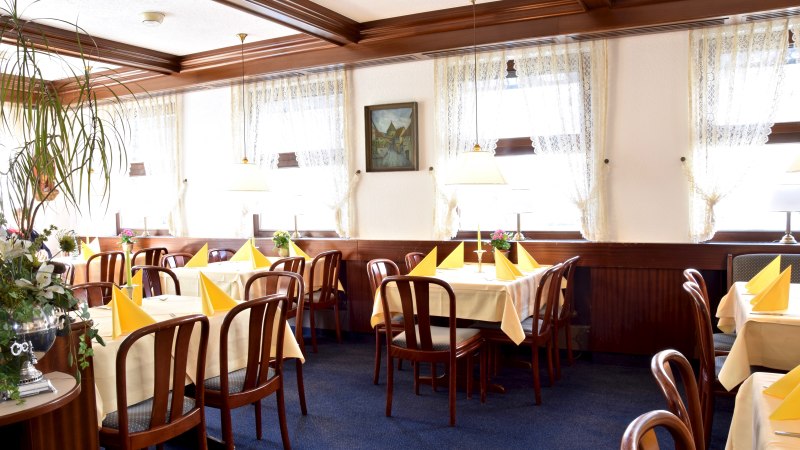 Gemütliches Restaurant mit Holzmöbeln, gelben Tischdecken und gefalteten Servietten. Große Fenster mit Spitzenvorhängen lassen viel Licht herein., © RestaurantPflum Gemütliches Restaurant mit Holzmöbeln, gelben Tischdecken und gefalteten Servietten. Große Fenster mit Spitzenvorhängen lassen viel Licht herein., © RestaurantPflum