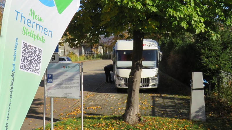 Wohnmobilstellplatz in Bad &Uuml;berkingen mit einem geparkten Wohnmobil, B&auml;umen und einem Schild mit QR-Code und Informationen., &copy; Archiv Gemeinde Bad &Uuml;berkingen