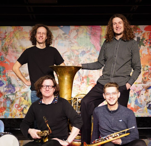 Vier Musiker der Magnus Mehl Tiny Brass Band posieren mit ihren Instrumenten vor einem bunten Hintergrund. Sie halten Saxophon, Trompete und Tuba., © Jazzclub Schwäbisch Hall e.V. Vier Musiker der Magnus Mehl Tiny Brass Band posieren mit ihren Instrumenten vor einem bunten Hintergrund. Sie halten Saxophon, Trompete und Tuba., © Jazzclub Schwäbisch Hall e.V.