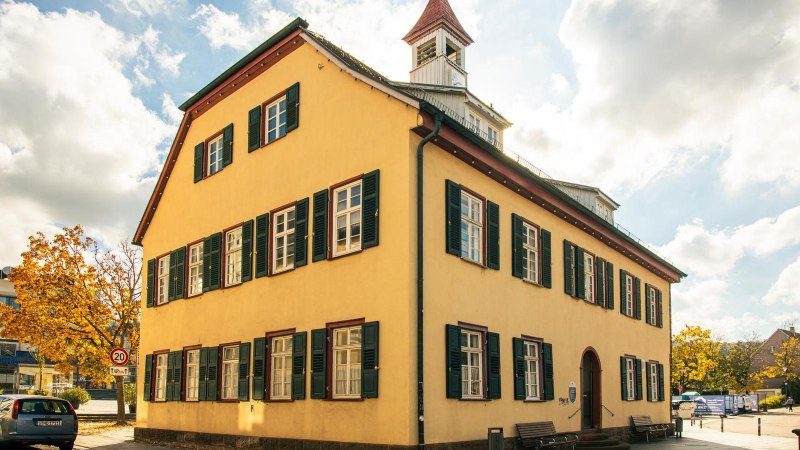 Ein historisches Geb&auml;ude in Gerlingen mit gelber Fassade und gr&uuml;nen Fensterl&auml;den, umgeben von modernen Bauten und herbstlichen B&auml;umen., &copy; Stuttgart-Marketing GmbH, Sarah Schmid