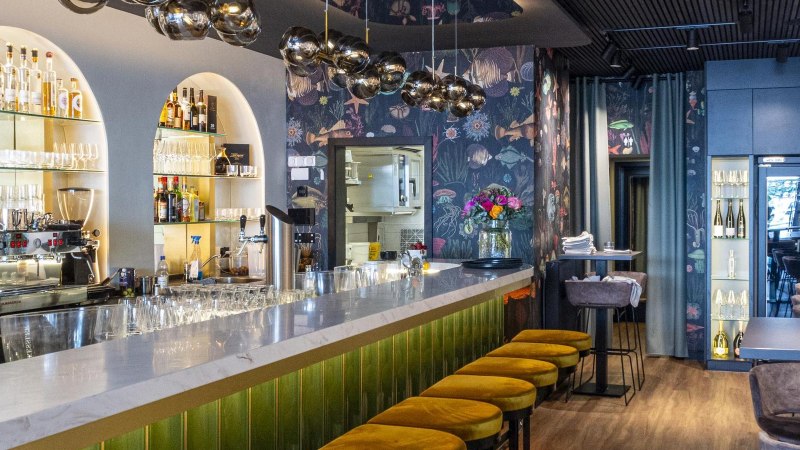 Eleganter Gastraum mit Marmortheke, gelben Hockern und stilvoller Beleuchtung. Die Bar ist gut best&uuml;ckt, mit Gl&auml;sern und Flaschen dekoriert., &copy; SMG, Sarah Schmid