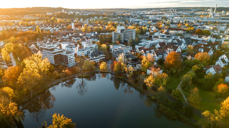 Luftaufnahme des Klostersees in Sindelfingen, umgeben von herbstlichen Bäumen und Wohngebäuden im Sonnenuntergang., © Christoph Partsch