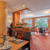 Eleganter Fr&uuml;hst&uuml;cksraum mit gedeckten Tischen, Pflanzen und gro&szlig;en Fenstern. Warme Farben und gem&uuml;tliche Atmosph&auml;re., &copy; PLAZA INN Rieker Stuttgart Hauptbahnhof