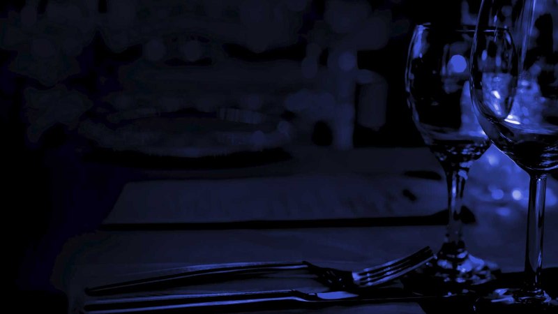 Ein dunkler, stimmungsvoller Tisch mit Weingl&auml;sern und Besteck, beleuchtet von schwachem blauen Licht., &copy; EINS + Alles/Christopherus e. V.